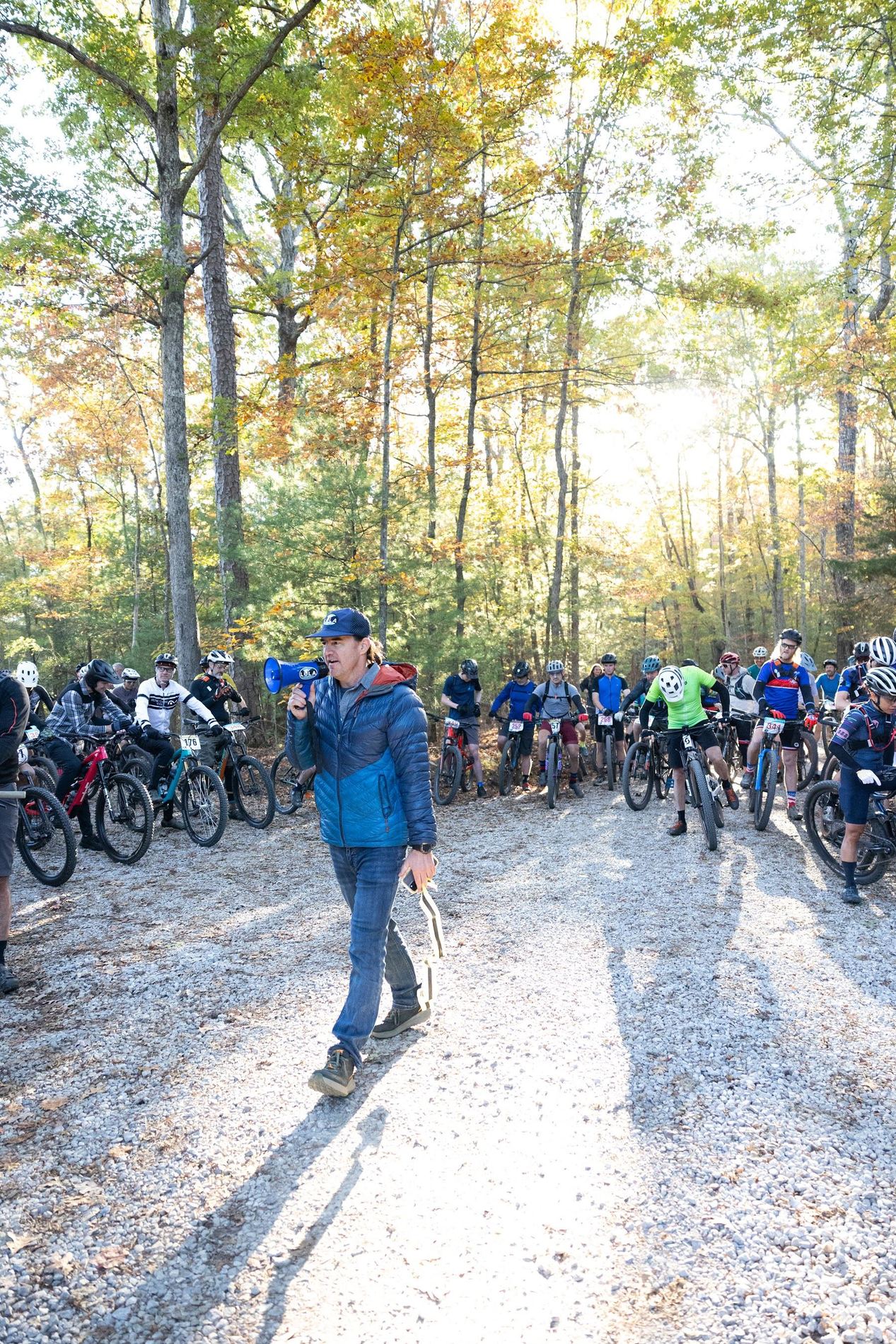 Riders lined up at the start under fall trees